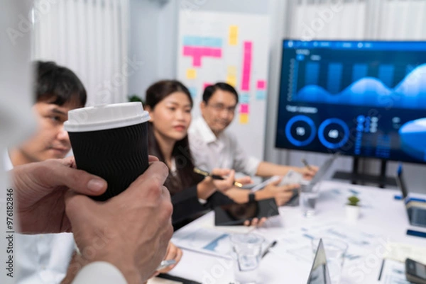 Fototapeta Businessman holding coffee cup while working on data analysis meeting, analyst team analyzing business intelligence or BI dashboard power for business insight and marketing planning. Prudent