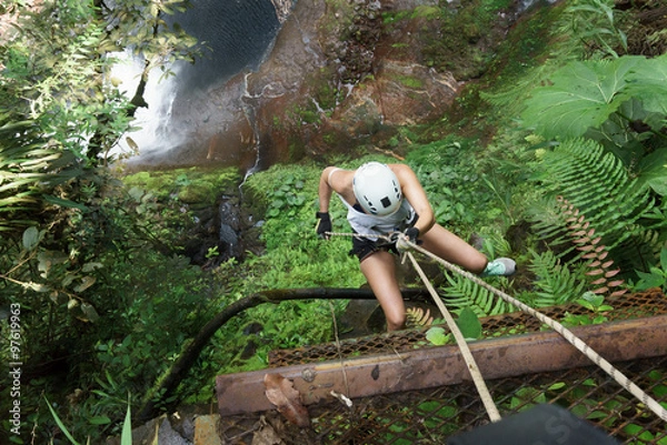 Obraz High angle view of a female climber climbing on rock in a forest, Costa Rica