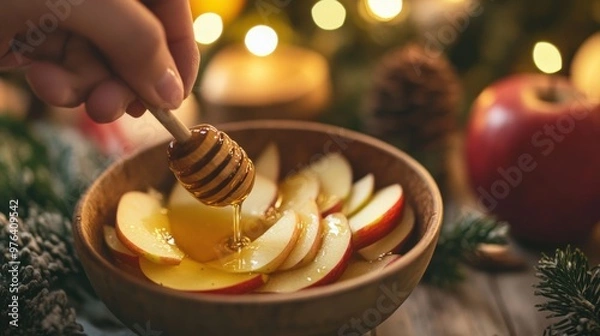 Fototapeta A close-up of a hand dipping apple slices into a bowl of honey during the holiday feast