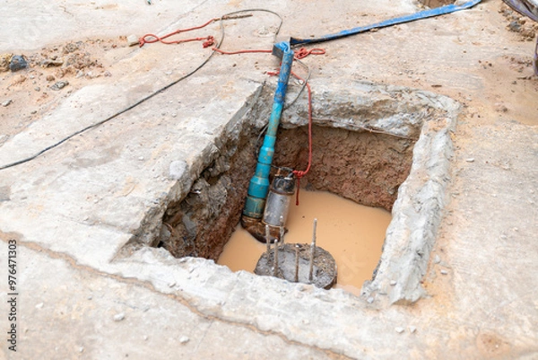 Fototapeta Submersible pump suck water out of pit for pour concrete foundation.