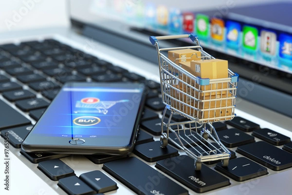 Obraz Zakupy online, zakupy internetowe i koncepcja e-commerce, nowoczesny telefon komórkowy z przyciskiem kupna na ekranie i koszyk pełen pudełek na klawiaturze laptopa