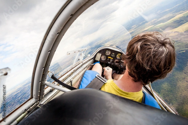 Obraz pilot in the cockpit of the plane, glider gliding in the air over cities and countryside