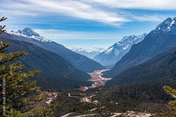 Obraz A captivating view of the Himalayas from Sikkim, India, featuring a lush valley, snow-capped peaks, and a winding river. Perfect for themes related to nature, travel, and scenic landscapes.