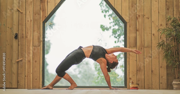 Obraz Woman doing Vinyasa yoga pose close to a window with black fitness outfit 01