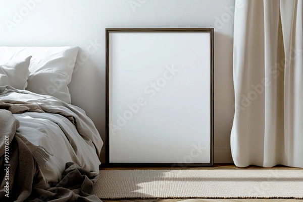 Fototapeta Empty wooden frame leaning against a wall next to a cozy bed with soft linens and curtains. Minimalist bedroom interior with natural light and shadows for art display and print