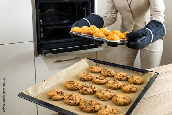 Obraz Double burden: business woman baking cupcakes in the kitchen