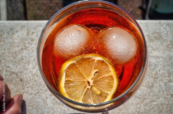 Fototapeta Aperol spritz cocktail seen from above, with ice and lemon forming a face