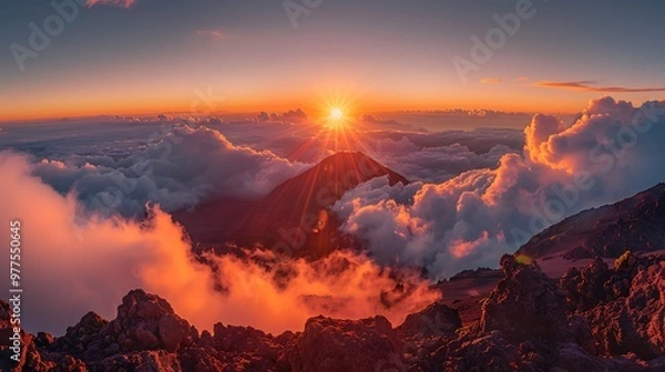 Fototapeta Watching the sunrise at Haleakalā National Park, Hawaii, unveils a surreal landscape as the sun rises above the clouds, illuminating the volcanic crater below. The dramatic colors and vast expanse 