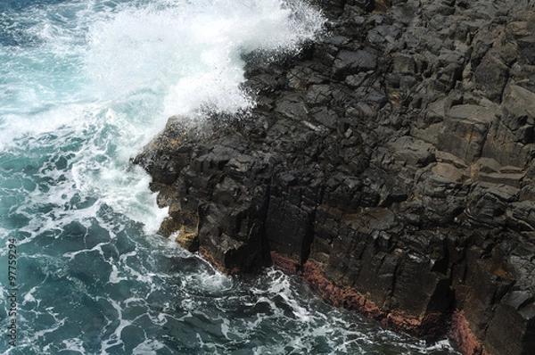 Fototapeta Waves crashing on volcanic cliffs.
