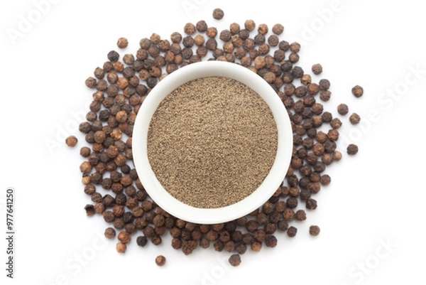 Fototapeta A bowl of Organic Black pepper (Piper nigrum) powder, placed over a heap of whole Black pepper. Isolated on a white background.