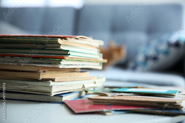 Fototapeta Pile of old books on white table in the room. Focus on books and blurred background
