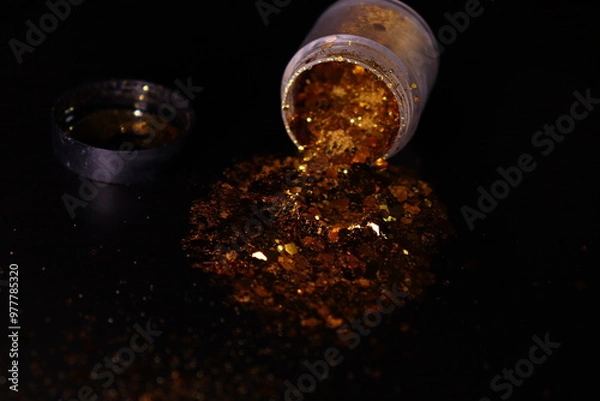 Obraz transparent jar with golden shiny shiny glitter on a black background