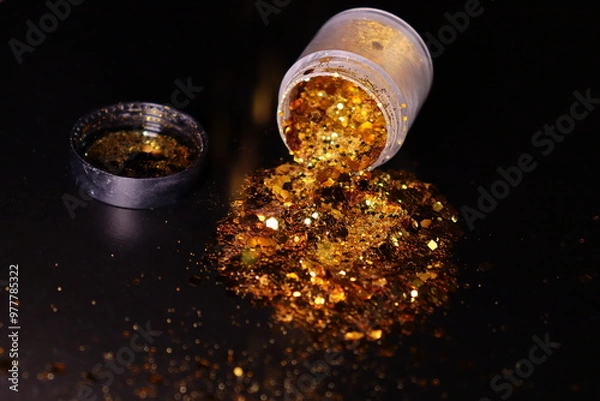 Obraz transparent jar with golden shiny shiny glitter on a black background
