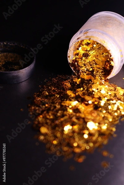 Obraz transparent jar with golden shiny shiny glitter on a black background
