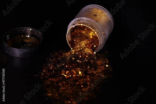 Obraz transparent jar with golden shiny shiny glitter on a black background