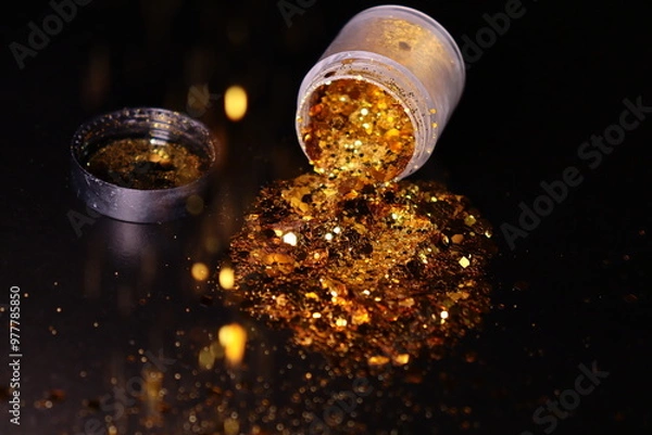 Obraz transparent jar with golden shiny shiny glitter on a black background