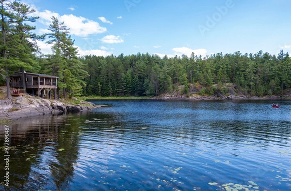 Obraz Water View of a Rustic Cottage Along the Shore of Pine Cove in French River Provincial Park and People Paddling in Their Canoe