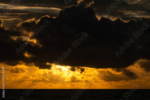 Fototapeta The sun's rays shine through the clouds, creating beautiful images above sea level.Beautiful, colorful, sunrise over the sea