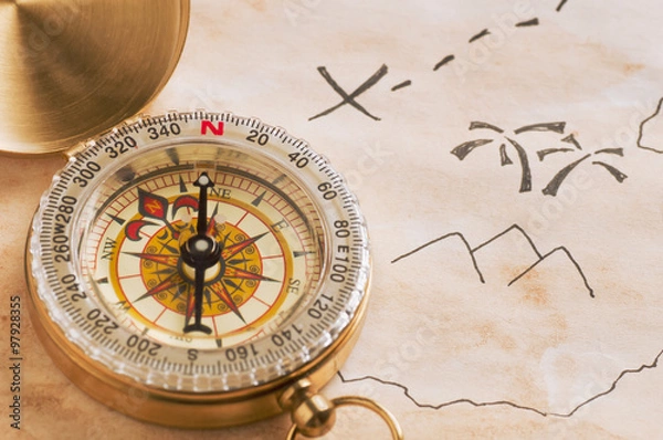 Obraz Closeup of compass over stained yellowed paper sheet with part of hand drawn treasure map