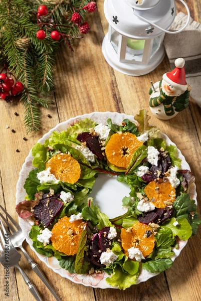 Fototapeta Christmas appetizer New year meal idea. Christmas wreath salad with beetroot, tangerines, feta cheese and pecans on the rustic table.