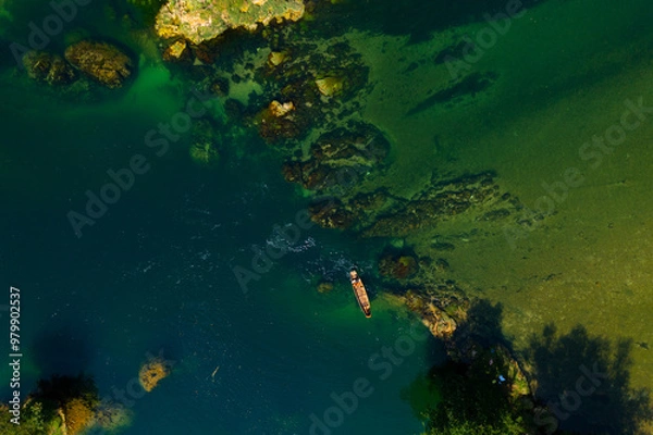 Fototapeta A man with a wooden boat in the middle of a beautiful clear river - top view