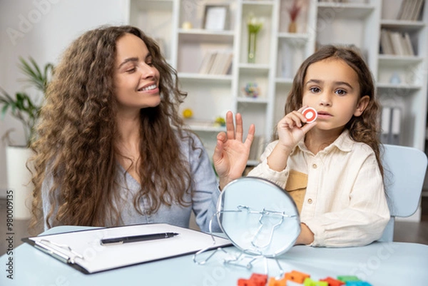 Fototapeta Child and doctor working on articulation and looking contented and concentrated