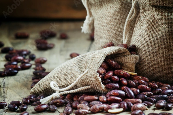 Fototapeta Dry beans in burlap sacks on old wooden background in rustic sty