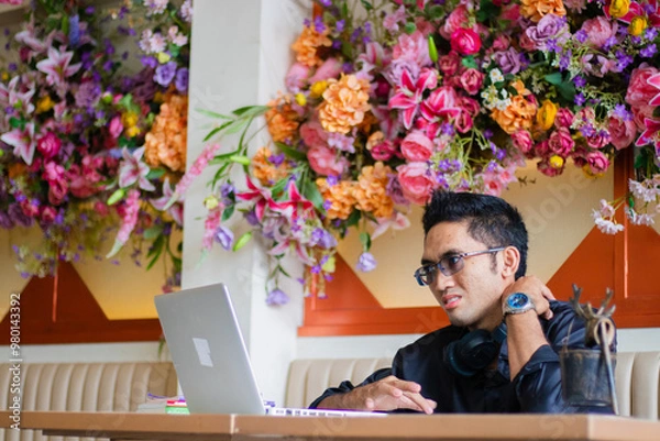 Fototapeta handsome asian male businessman in pain shoulder pain in front of laptop computer on table, sitting in cafe workplace. for health, education, technology, lifestyle content