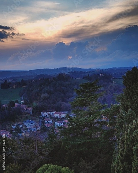 Fototapeta Aerial view of Conegliano, Italy, from the top of Castello di Conegliano, captured in blue hour with intentional dark tones to highlight the dramatic evening sky and landscape of the village below.