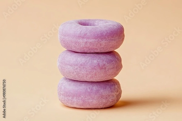 Obraz Three purple donuts stacked on top of each other against a light orange background.