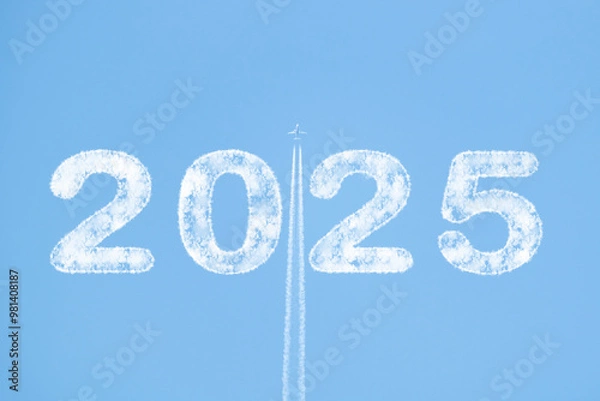 Fototapeta Plane soaring through blue sky with 2025 text in clouds and white smoke trail