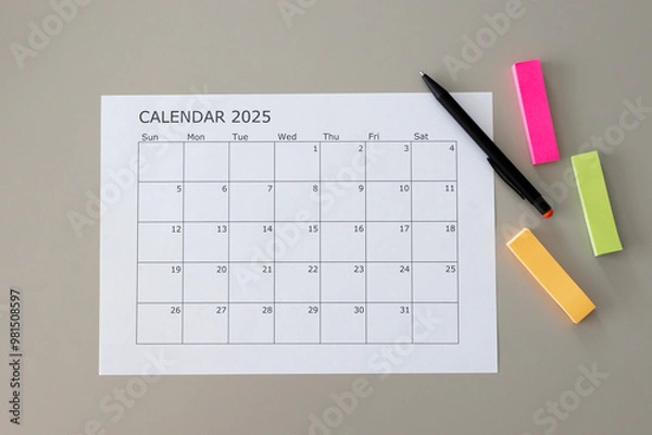Fototapeta Blank calendar with 2025 writing and a pen and colorful note stickers on table. Space for text
