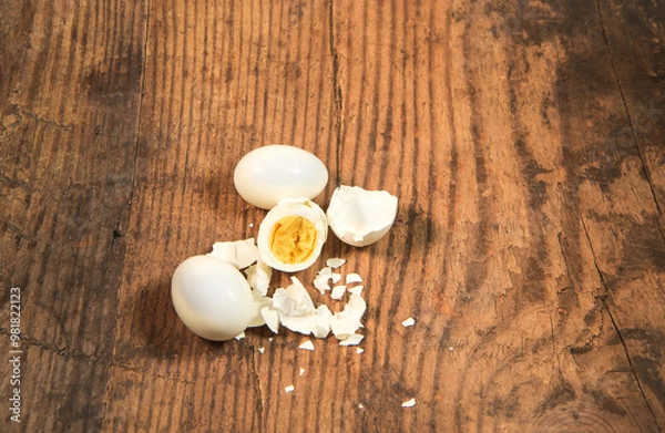 Fototapeta Peeled fresh organic eggs isolated on a rustic wooden table with advertising space.