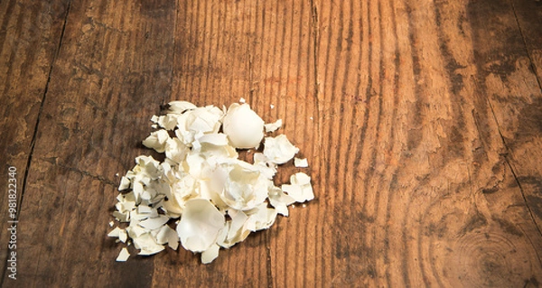 Fototapeta White egg shells isolated on a rustic wooden table with advertising space. 
