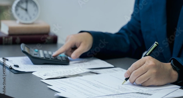 Obraz Businessman calculates taxes using calculator and pen to writing note.