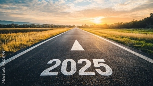 Fototapeta A deserted road with "2025" painted on its surface, heading towards a sunrise or sunset, symbolizing the journey into the future or a new year.
