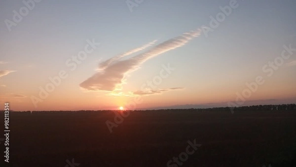 Fototapeta Fluffy white cloud in the setting sun shaped like a rabbit jumping over the horizon.