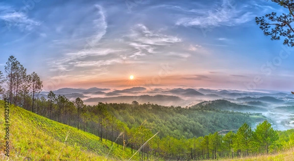 Fototapeta Panoramic sun rises above pine forests as the sun rises, clouds will gradually fade out gradually to vast green pine forests on the high hills greet the new day