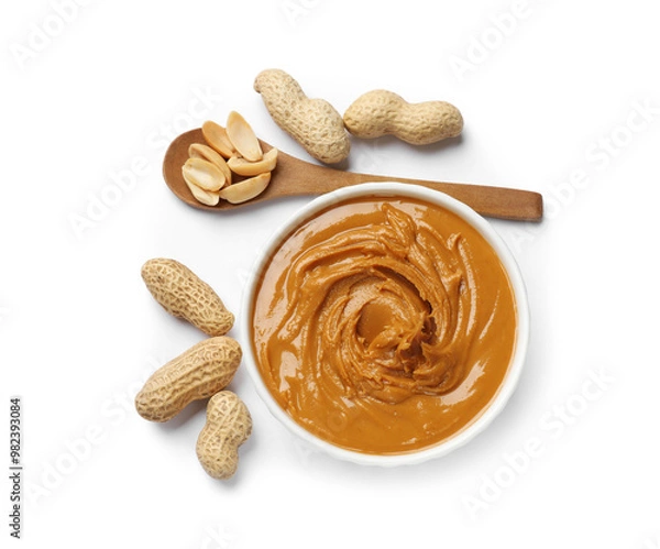 Fototapeta Tasty peanut butter in bowl, spoon and groundnuts isolated on white, top view