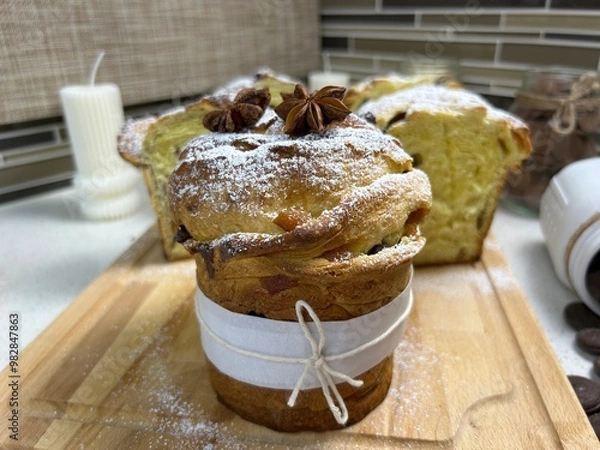 Obraz A beautifully baked Paska, a Ukrainian traditional Easter sweet bread, dusted with powdered sugar and topped with star anise, in a cozy kitchen setting.