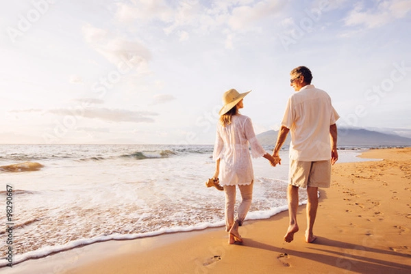 Obraz Dojrzała para spacerująca po plaży o zachodzie słońca