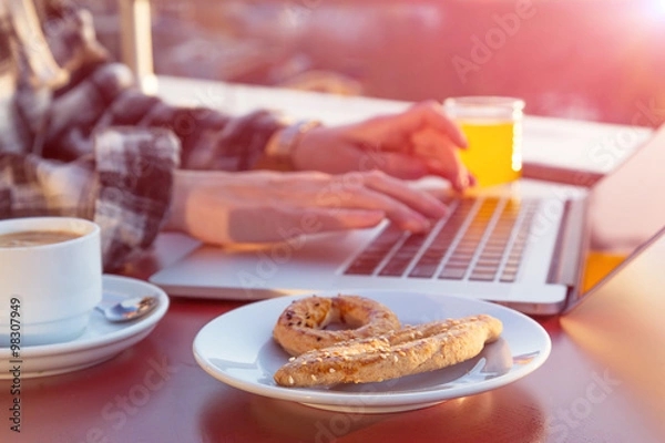 Obraz Person sitting at wood desk working on laptop computer drinking coffee