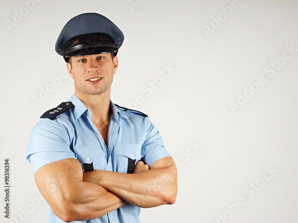 Fototapeta Portrait of smiling muscular policeman in police cap, you can write some text in right