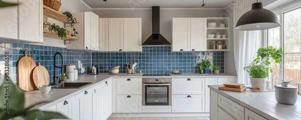 Fototapeta Modern Scandinavian kitchen with an efficient layout, custom white cabinetry, and a pop of color from a blue tile backsplash