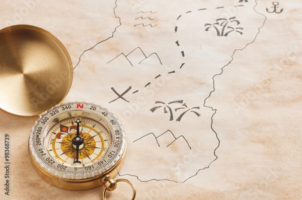 Obraz Zbliżenie kompasu na poplamione pożółkłe arkusze papieru z częścią mapy skarbów wyciągnąć rękę