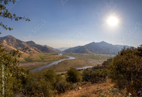 Fototapeta A scenic view of Lake Kaweah and the surrounding golden hills near Three Rivers, California, showcasing the dry lakebed and the winding Kaweah River under the Sierra Nevada foothills.