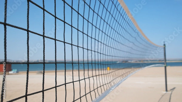 Fototapeta Volleyball net close-up and sand court on the seashore ready for play