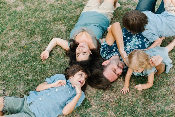 Obraz Happy young hipster family having fun while running, bowl,  rising up, piggyback ride their children in park on summer sunset
