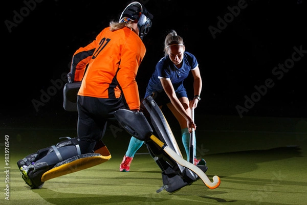 Fototapeta Goalkeeper and attacker engage in intense field hockey match against black background