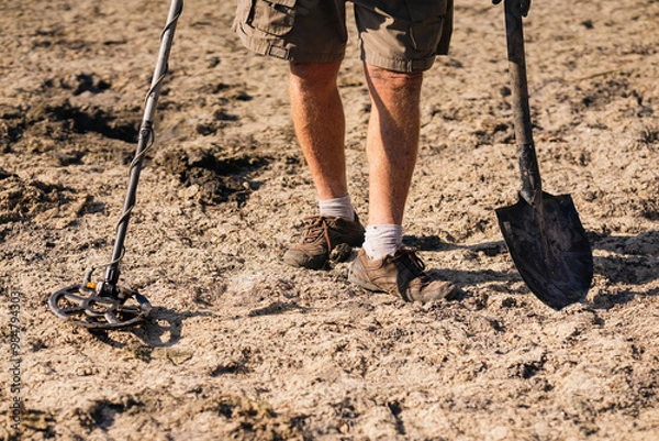 Fototapeta A man with a metal detector looking for antique valuables in the ground.